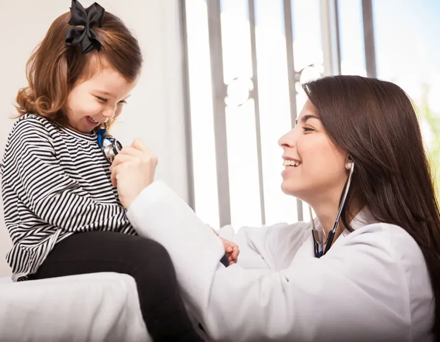 Pediatric Nurse Practitioner Smiling with Young Patient Reading Heart Rate with Stethoscope